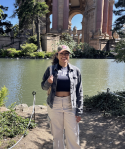 A woman smiling with a body of water behind her. 
